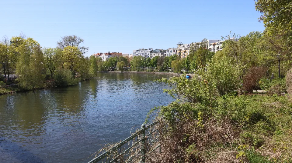 Weitläufiger Blick über das Wasser zu grünen Bäumen und hellen Häusern.